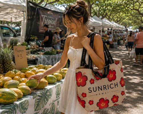 A woman carries the SUNRICH Hibiscus Sun Market Tote while shopping for papaya at a Hawaiʻi farmers market